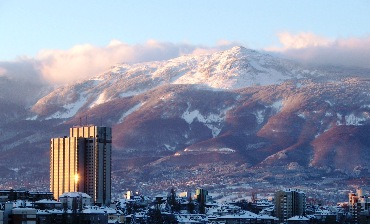This photo of the skyline of Sofia, Bulgaria with the Vitosha Mountains rising in the background was taken by "podoboq" and is used courtesy of the Creative Commons Attribution 2.0 License. (http://commons.wikimedia.org/wiki/File:Sofia-vitosha-kempinski.jpg)